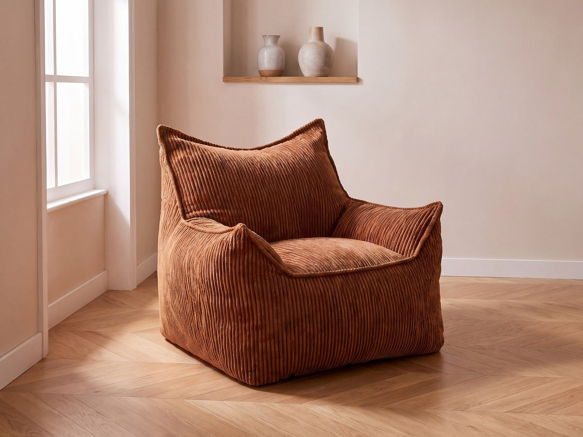 Pouf fauteuil en velours côtelé caramel dans un salon cosy avec parquet en chevrons